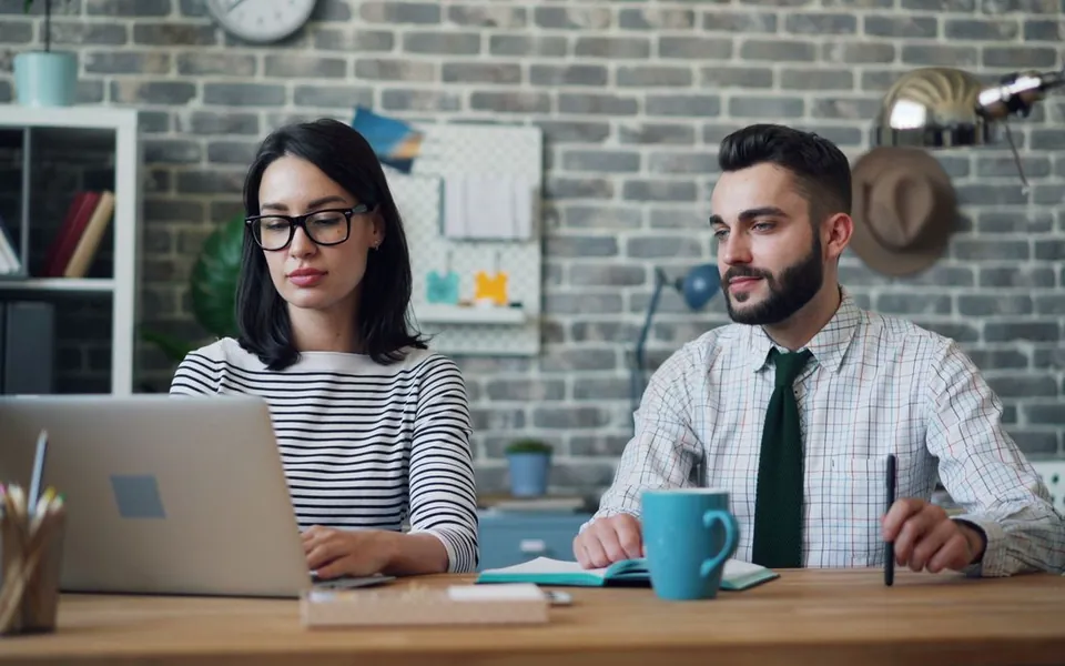 Een man en een vrouw werken samen aan een bureau met een laptop